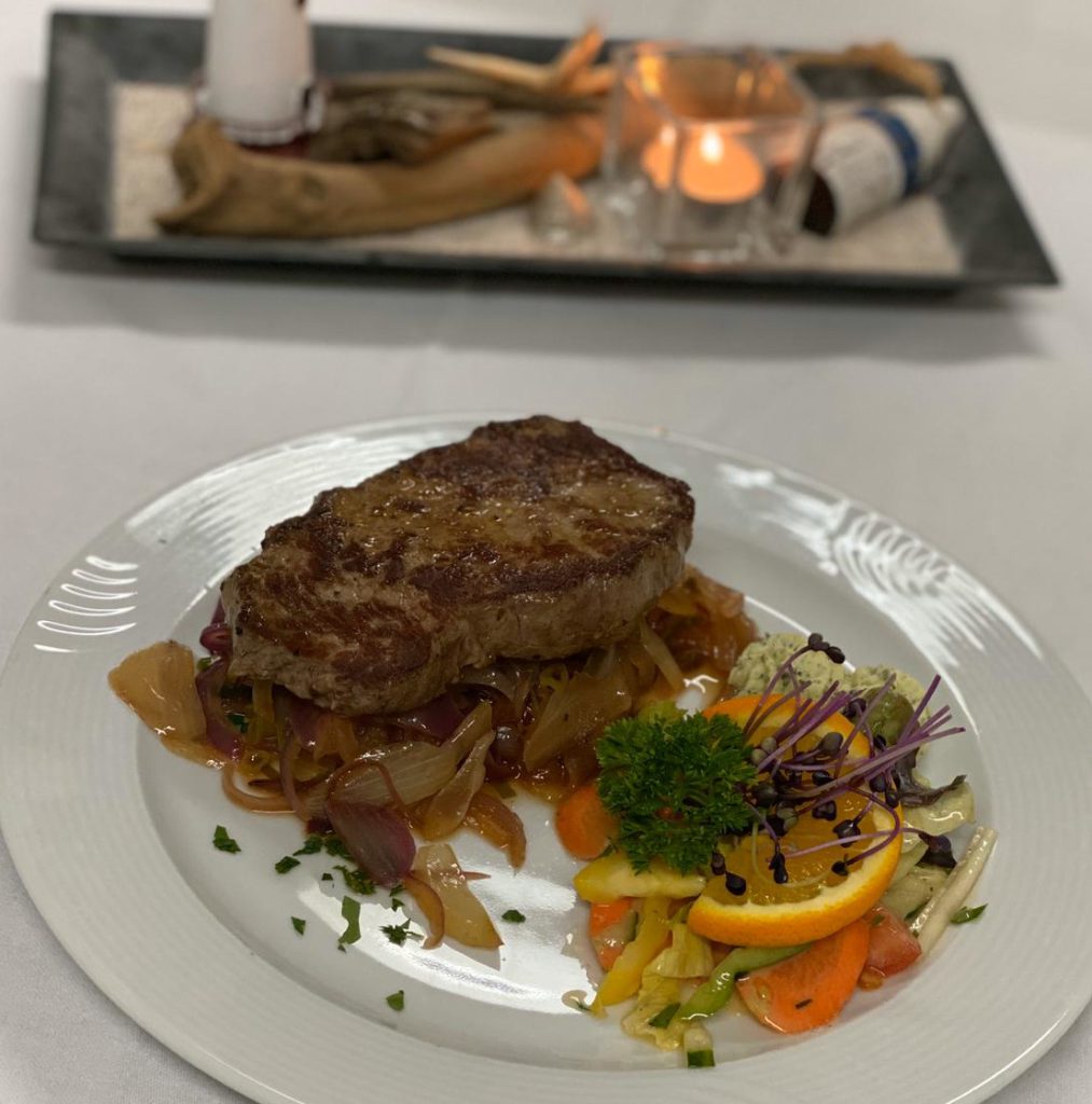 Rumpsteak "Kräuterbutter" mit geschmorten Zwiebeln, dazu reichen wir Pommes frites und einen bunten Salatteller